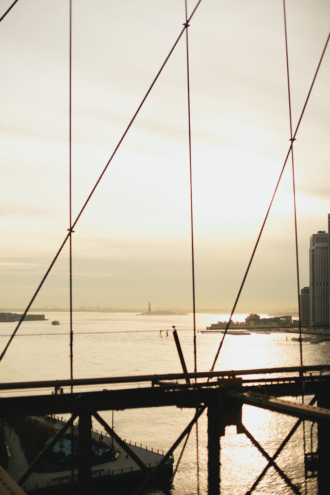 statue of liberty as seen from the brooklyn bridge near sunset